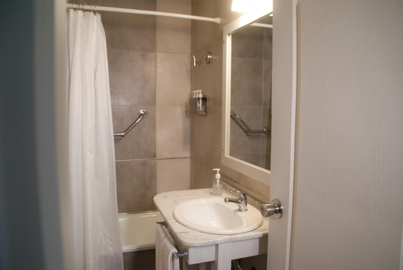 Baño con ducha, lavatorio y espejo
